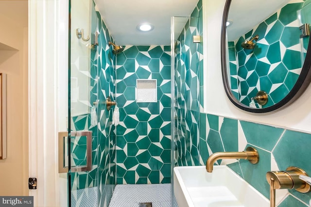 full bathroom with tile walls, a shower stall, a sink, and recessed lighting