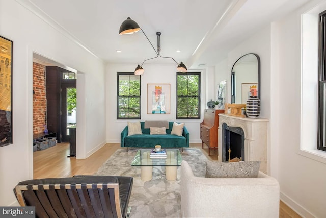 living room featuring light wood-style flooring, baseboards, crown molding, a fireplace, and recessed lighting