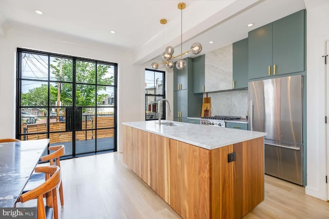 kitchen featuring appliances with stainless steel finishes, a sink, light wood-style flooring, modern cabinets, and tasteful backsplash