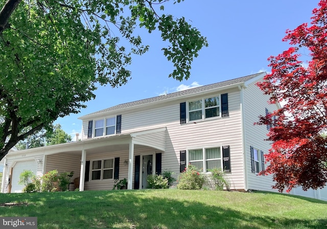 traditional-style house featuring a front yard and an attached garage