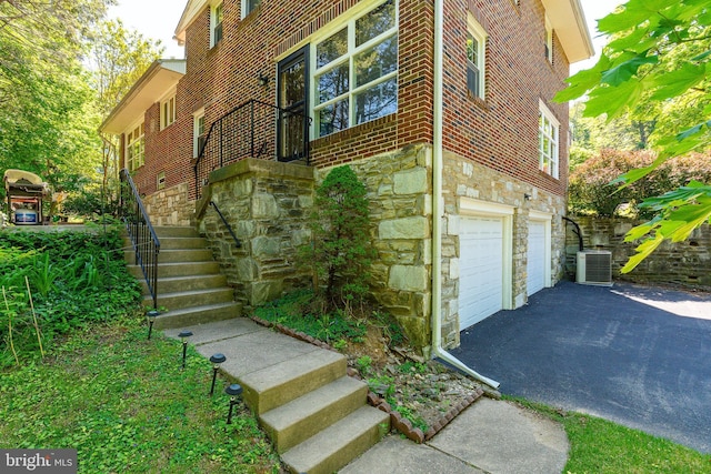 1128 Coventry Rd, Cheltenham, PA 19012 - view of side of home with stone siding, asphalt driveway, central air condition unit, and stairs