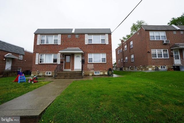 townhome / multi-family property with brick siding, a front yard, a wall unit AC, and central AC unit