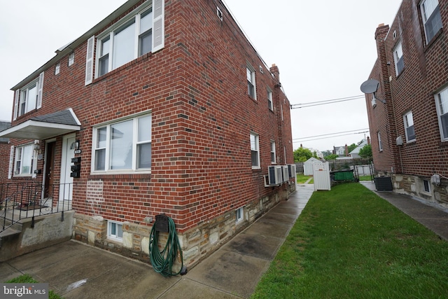 view of home's exterior featuring brick siding, a lawn, and central AC