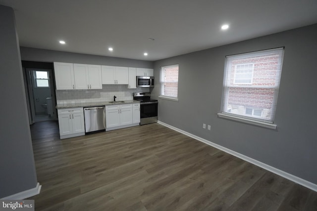 kitchen with stainless steel appliances, white cabinetry, baseboards, healthy amount of natural light, and recessed lighting
