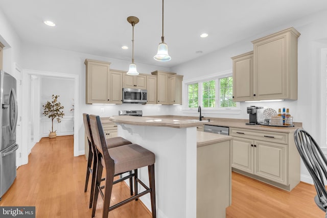 14745 Jennifer Ct, Issue, MD 20645 - kitchen with stainless steel appliances, cream cabinetry, a kitchen bar, light countertops, and light wood-type flooring