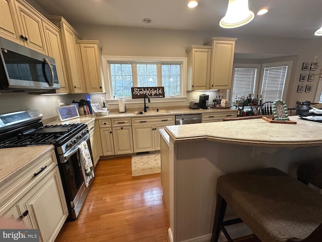 14745 Jennifer Ct, Issue, MD 20645 - kitchen with appliances with stainless steel finishes, a sink, a breakfast bar, light countertops, and light wood-style flooring