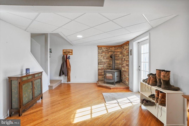 6194 Milo School Rd, Great Cacapon, WV 25422 - living room featuring a paneled ceiling, a wood stove, light wood-style floors, stairs, and baseboards
