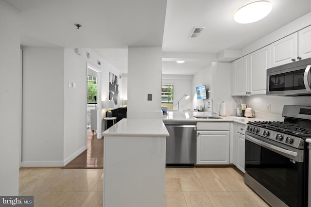 1045 N Utah St Unit 2-304, Arlington, VA 22201 - kitchen with stainless steel appliances, a peninsula, a sink, white cabinetry, and light countertops