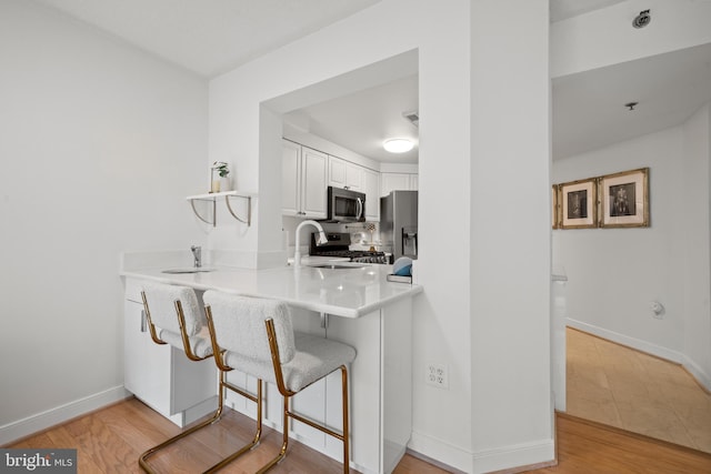1045 N Utah St Unit 2-304, Arlington, VA 22201 - kitchen featuring stainless steel appliances, a sink, white cabinetry, a breakfast bar, and a peninsula