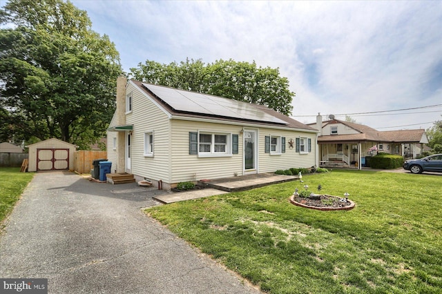 view of front of home with a shed, roof mounted solar panels, an outdoor structure, a chimney, and driveway
