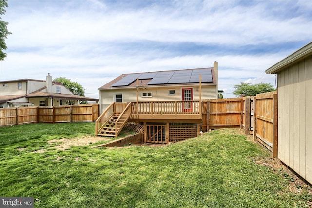 back of property featuring stairway, a deck, and roof mounted solar panels