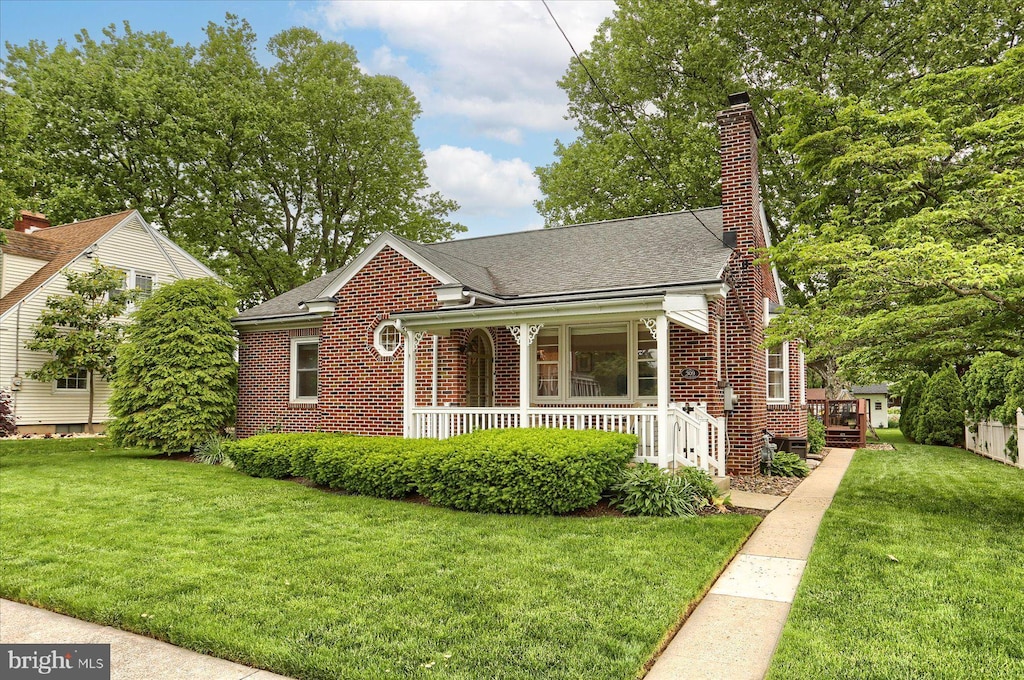 309 W Oak St, Palmyra, PA 17078 - view of front of property with brick siding, a front yard, covered porch, and roof with shingles