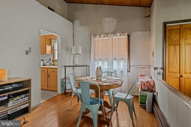 dining space with light wood-style flooring, healthy amount of natural light, wood ceiling, a wainscoted wall, and high vaulted ceiling