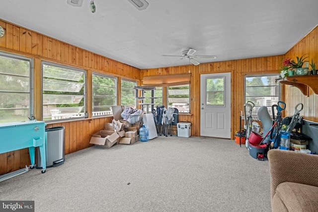 sunroom / solarium with ceiling fan, wooden walls, and carpet floors