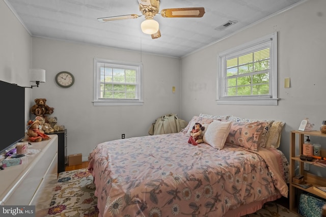 bedroom with crown molding, wood finished floors, and a ceiling fan
