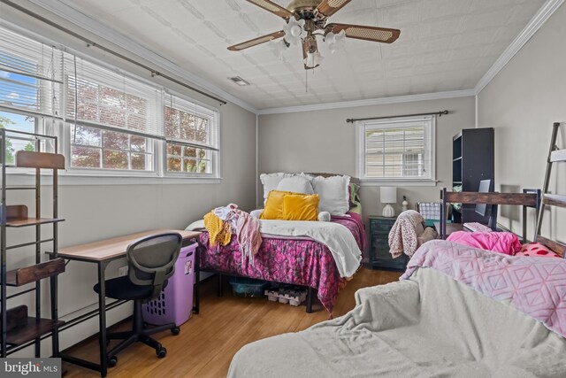 bedroom with multiple windows, wood finished floors, ornamental molding, baseboard heating, and an office area