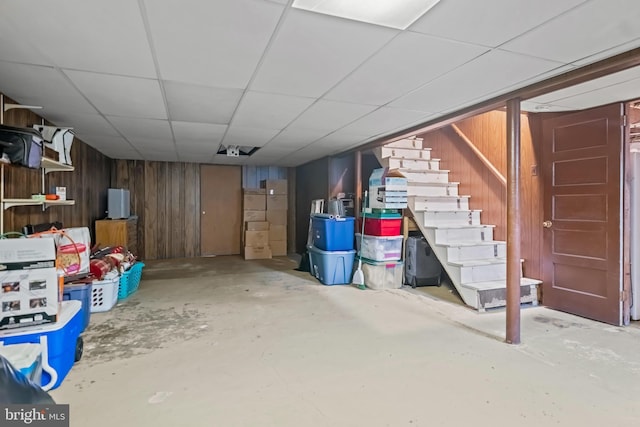 finished below grade area with stairs, wooden walls, and a drop ceiling