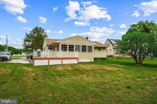 back of house featuring a yard, a sunroom, and a wooden deck