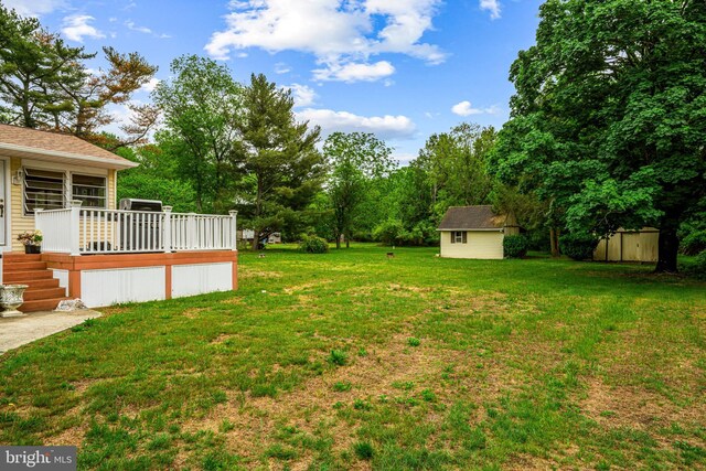 view of grassy yard with a shed, an outbuilding, and a wooden deck