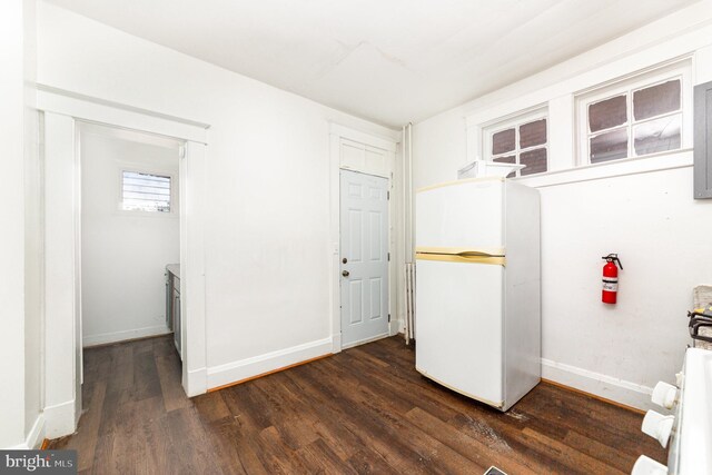 clothes washing area with dark wood-style floors and baseboards