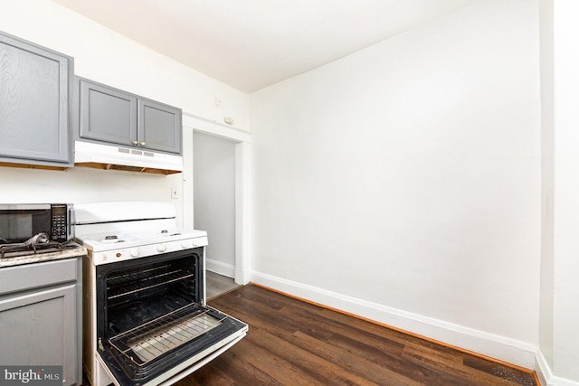 kitchen featuring under cabinet range hood, gray cabinets, white range with gas stovetop, baseboards, and dark wood-type flooring