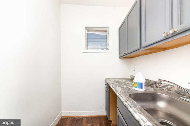 laundry area featuring baseboards, dark wood finished floors, and a sink