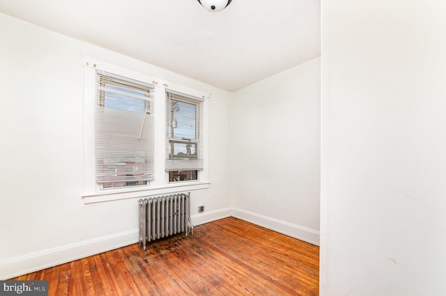 empty room with radiator heating unit, baseboards, and hardwood / wood-style floors