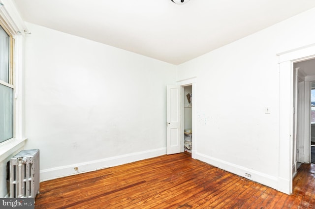 unfurnished room featuring radiator heating unit, wood-type flooring, and baseboards