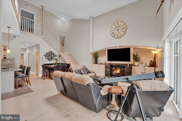 320 Hummingbird Way Unit 302, Lake Harmony, PA 18624 - living room featuring high vaulted ceiling, a glass covered fireplace, light wood finished floors, and stairs