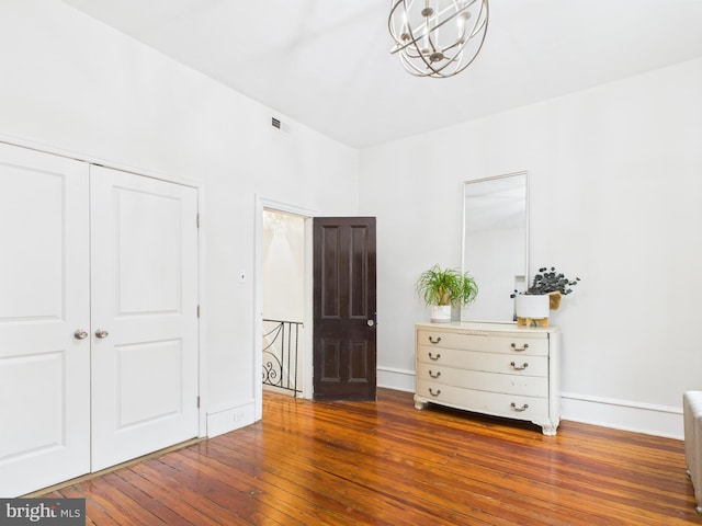 bedroom with a chandelier, wood-type flooring, a closet, and baseboards