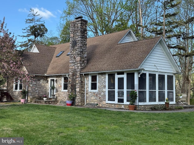 back of house with a shingled roof, a sunroom, a chimney, and a yard