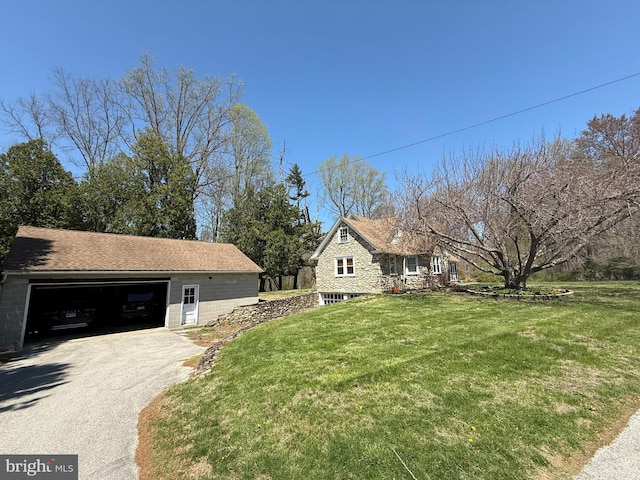 view of front of house featuring a garage, a front lawn, an outbuilding, and driveway