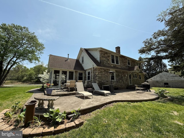 back of property featuring stone siding, a patio, a chimney, and a yard