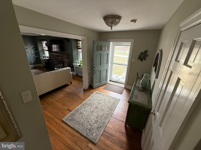 foyer with wood finished floors, a fireplace, and baseboards