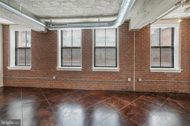 916 G St NW Unit 505, Washington, DC 20001 - empty room featuring brick wall, plenty of natural light, and dark tile patterned floors