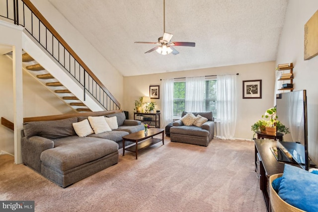 carpeted living area featuring ceiling fan, stairway, high vaulted ceiling, a textured ceiling, and baseboards