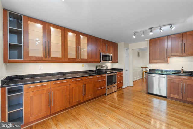 4516 4th Rd N, Arlington, VA 22203 - kitchen featuring appliances with stainless steel finishes, a sink, light wood-style floors, glass insert cabinets, and brown cabinetry