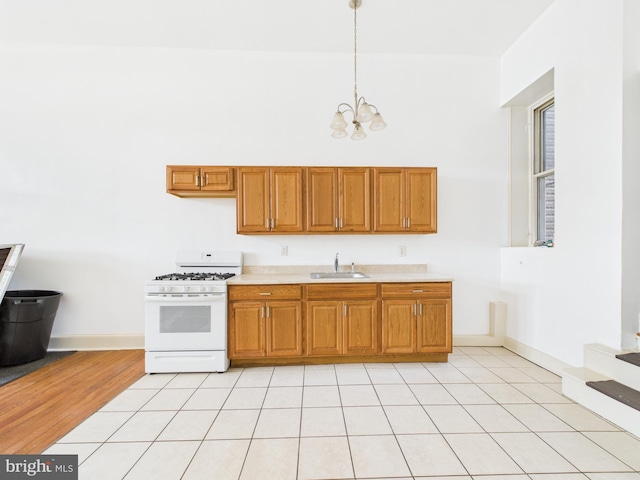 4712 Woodland Ave, Philadelphia, PA 19143 - kitchen featuring white gas range, a sink, a chandelier, and brown cabinets