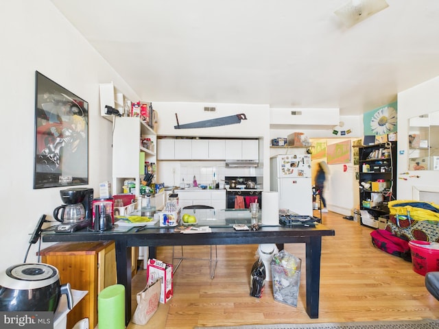 4712 Woodland Ave, Philadelphia, PA 19143 - kitchen featuring freestanding refrigerator, wood finished floors, under cabinet range hood, electric range, and backsplash