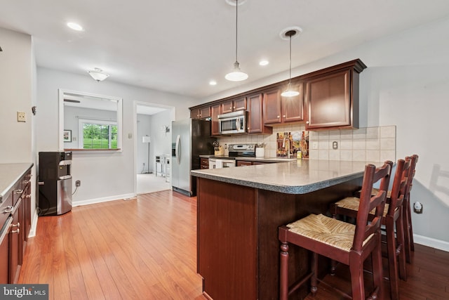 1415 Aspen Ct, West Chester, PA 19380 - kitchen with appliances with stainless steel finishes, backsplash, a kitchen breakfast bar, baseboards, and light wood-style flooring