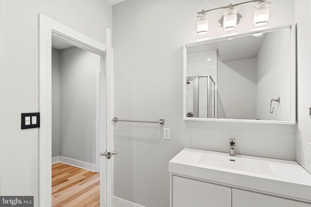 full bath featuring a shower stall, wood finished floors, vanity, and baseboards
