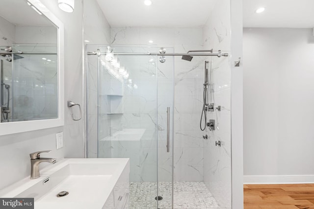 bathroom with a marble finish shower, wood finished floors, recessed lighting, and vanity