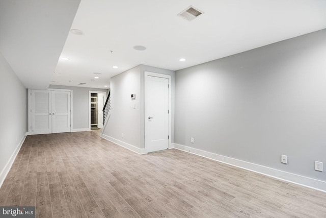unfurnished living room with light wood-style floors, baseboards, stairway, and recessed lighting