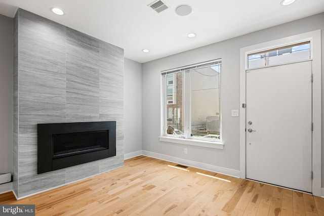 entryway featuring healthy amount of natural light, a tile fireplace, wood finished floors, baseboards, and recessed lighting