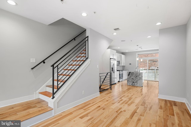staircase with wood finished floors, baseboards, and recessed lighting