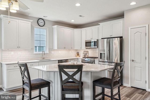 1723 Magnolia Ct, Garnet Valley, PA 19060 - kitchen with a sink, appliances with stainless steel finishes, a breakfast bar, white cabinetry, and tasteful backsplash