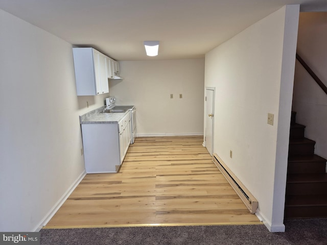 kitchen with baseboard heating, electric range oven, baseboards, light countertops, and white cabinetry
