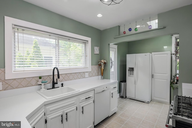 kitchen with white appliances, a sink, white cabinetry, light countertops, and decorative backsplash