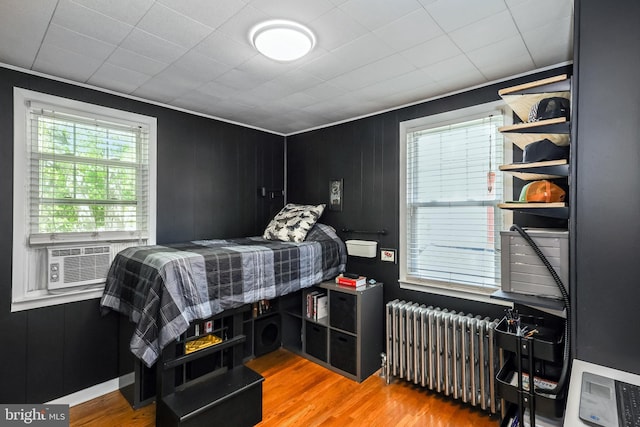 bedroom featuring radiator, cooling unit, and wood finished floors