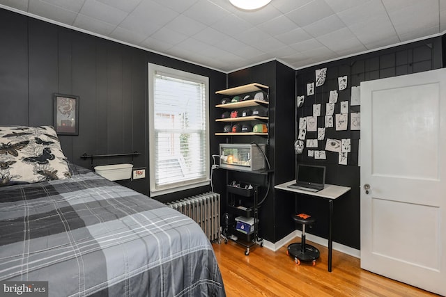 bedroom featuring radiator heating unit, wood finished floors, and crown molding